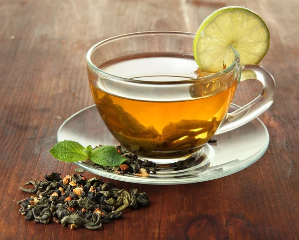 Taza transparente de té verde con lima sobre fondo de madera — Foto de Stock