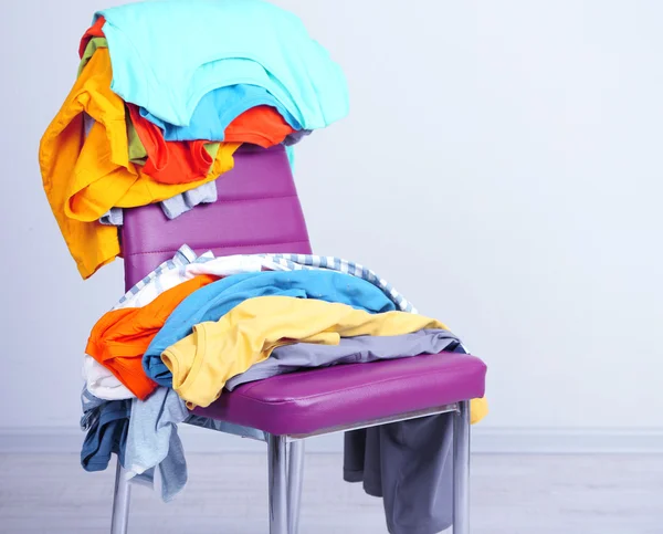 Heap of clothes on color chair — Stock Photo, Image