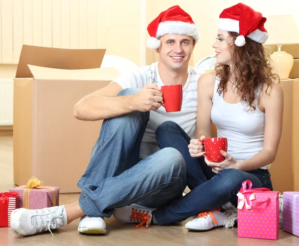 Casal jovem com caixas em nova casa celebrando o Ano Novo — Fotografia de Stock