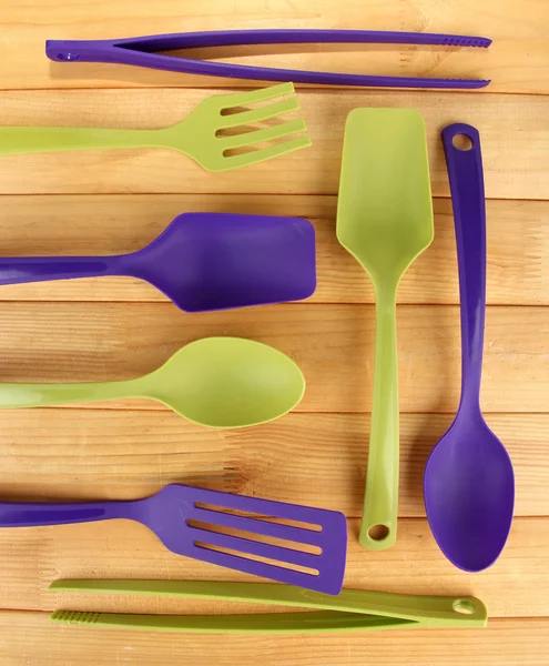 Plastic kitchen utensils on wooden background — Stock Photo, Image