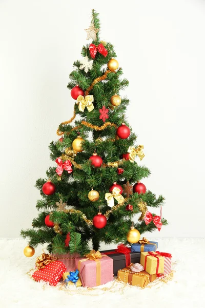 Geschmückter Weihnachtsbaum mit Geschenken auf grauem Wandhintergrund — Stockfoto