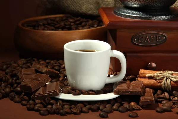 Tasse de café, moulin et grains de café sur fond brun — Photo