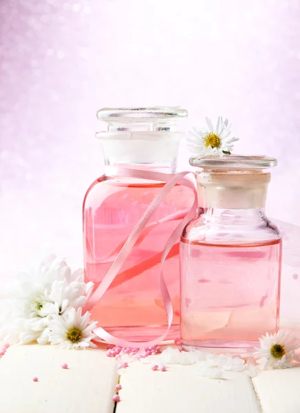 Bouteilles en verre avec essence de couleur, sur fond rose — Photo