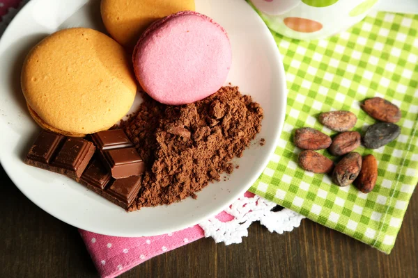 Sweets and cocoa powder on plate on wooden table — Stock Photo, Image