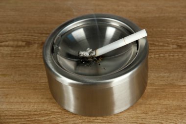 metal kül tablası ve ahşap masa üzerinde Sigara