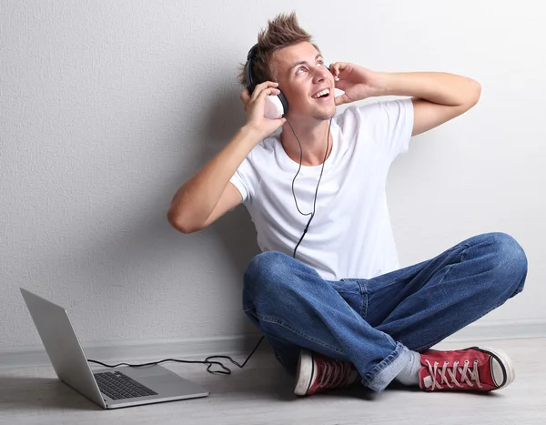 Knappe jongeman, luisteren naar muziek op een grijze achtergrond — Stockfoto