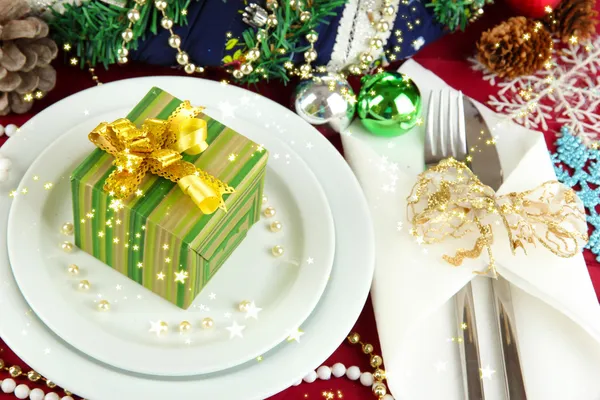 Small Christmas gift on plate on serving Christmas table background close-up — Stock Photo, Image