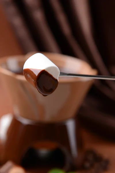 Шоколадний фонтан з зефірними цукерками на коричневому фоні — стокове фото
