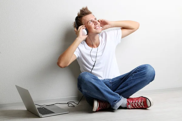 Joven guapo escuchando música sobre fondo gris — Foto de Stock