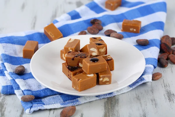 Many toffee on plate on napkin on wooden table — Stock Photo, Image