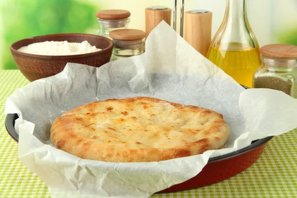 Pita bread in oven-tray with spices on tablecloth on bright background — Stock Photo, Image