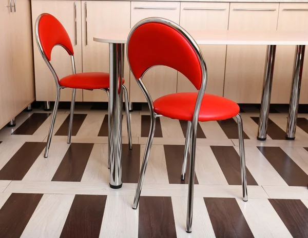 Современные красные стулья рядом со столом на кухне — стоковое фото