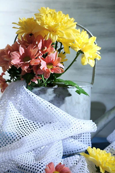 Композиція з красивими квітами в балончику для поливу, і тканиною на кольоровому дерев'яному фоні — стокове фото