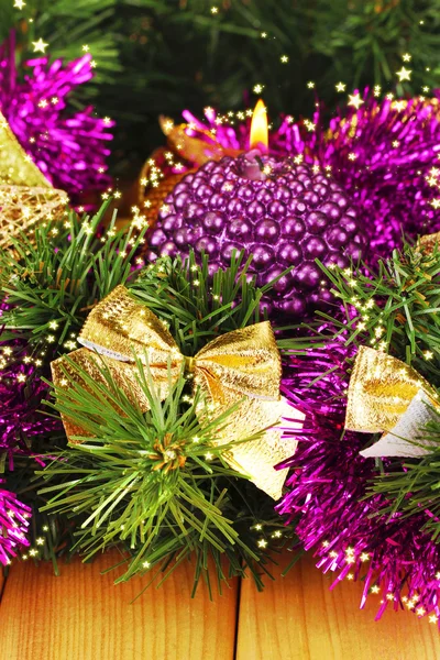 Weihnachtskomposition mit Kerzen und Dekorationen in lila und goldenen Farben auf Holzgrund — Stockfoto