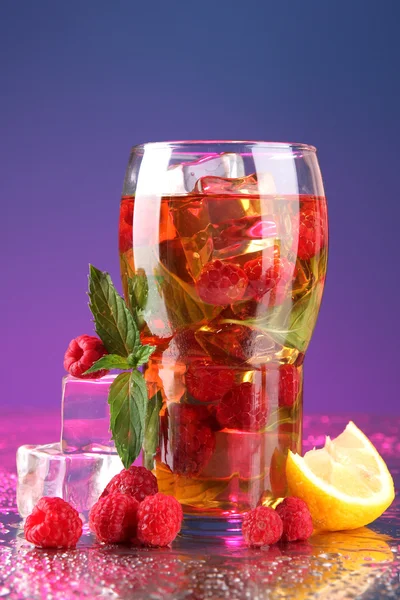 Iced tea with raspberries and mint on blue background — Stock Photo, Image