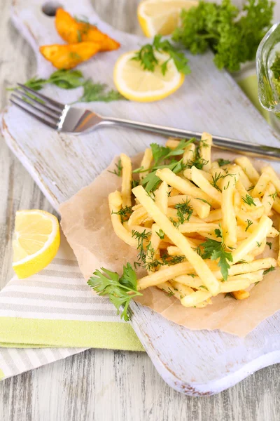 Pommes frites auf Transparentpapier auf Serviettenholztisch — Stockfoto