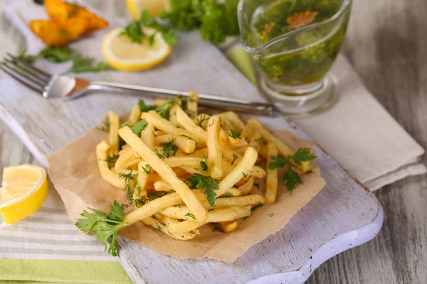 Pommes frites auf Transparentpapier auf Serviettenholztisch — Stockfoto