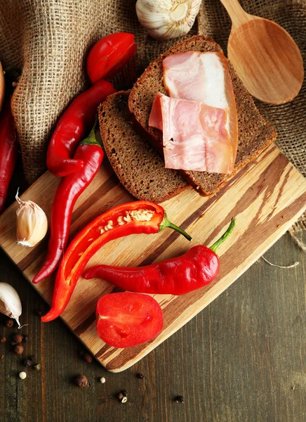 Composition with salsa sauce on bread,, red hot chili peppers and garlic, on sackcloth, on wooden background — Stock Photo, Image