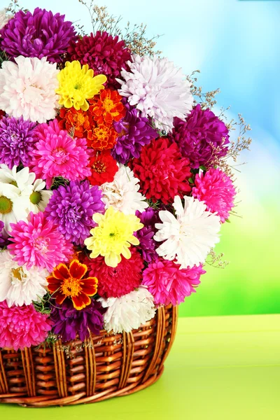 明るい背景上のテーブルに枝編み細工品バスケットの菊の花の美しい花束 — ストック写真