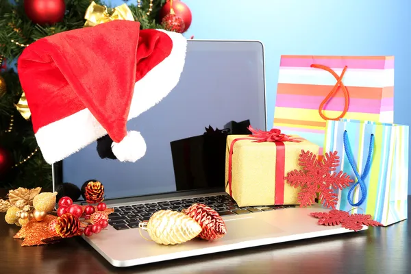 Laptop met geschenken op tafel op blauwe achtergrond — Stockfoto