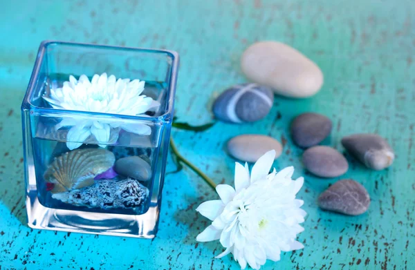 Decorative vase with flower, water and stones on wooden table close-up — Stock Photo, Image