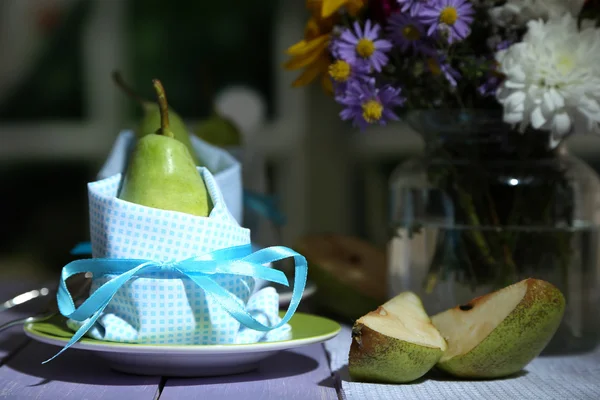 Peras en servilletas en platos sobre mesa de madera sobre fondo brillante — Foto de Stock