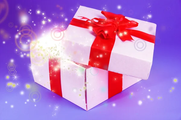 Gift box with bright light on it on purple background — Stock Photo, Image