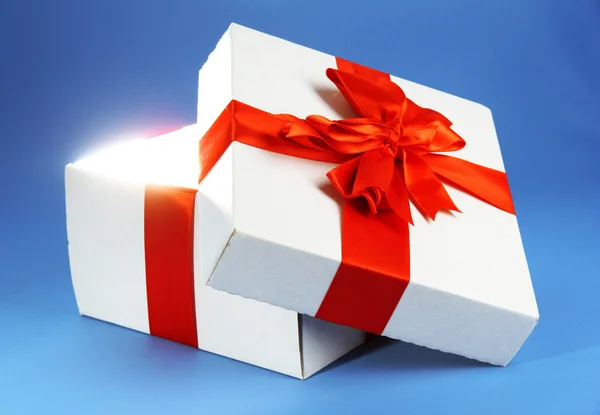 Geschenkbox mit hellem Licht auf blauem Hintergrund — Stockfoto