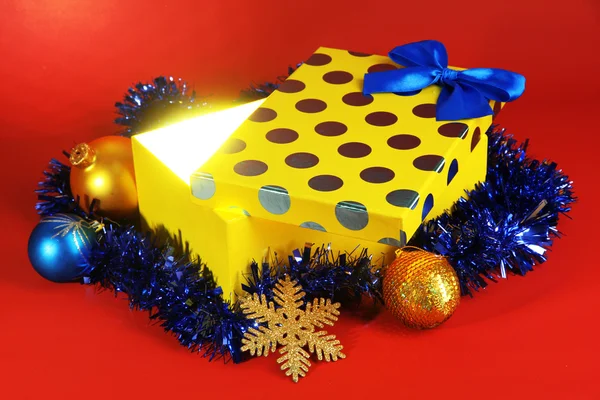 Gift box with bright light on it on red background — Stock Photo, Image