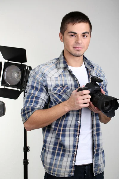 Handsome photographer with camera, on photo studio background