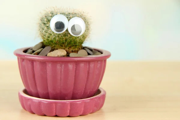 Cactus en maceta con ojos divertidos, sobre mesa de madera —  Fotos de Stock