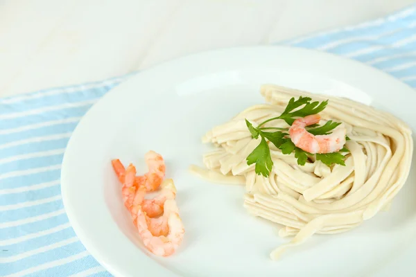 Pasta with shrimps on white plate, on wooden background — Stock Photo, Image