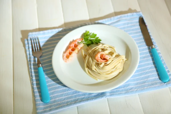 Паста с креветками на белой тарелке, на деревянном фоне — стоковое фото