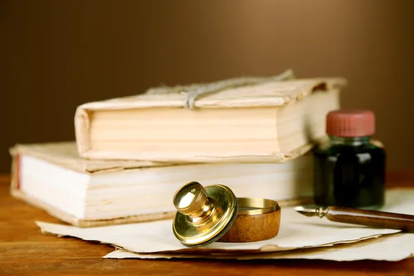 Sello de madera, libros y papeles viejos sobre mesa de madera — Foto de Stock