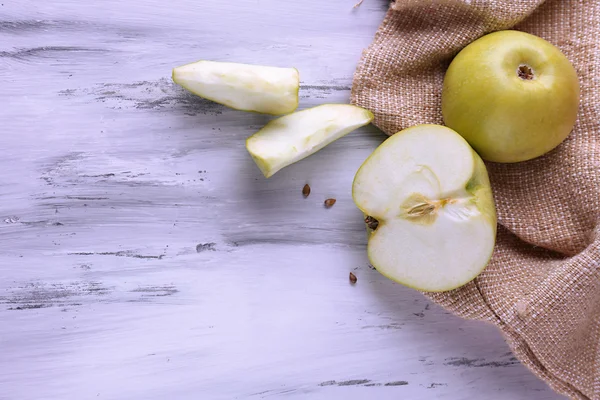 Apples and sackcloth on on wooden background — Stock Photo, Image