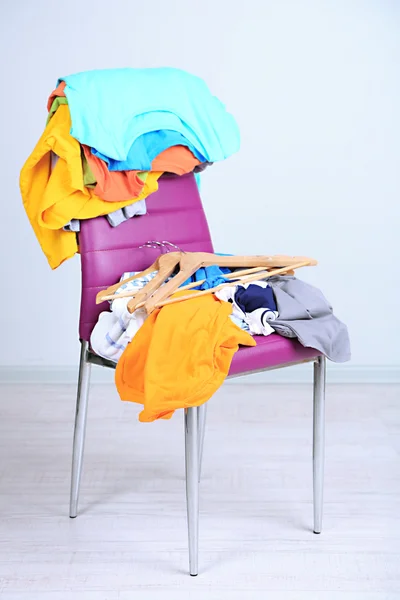 Heap of clothes on color chair, on gray background — Stock Photo, Image