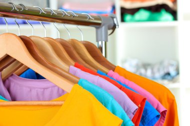 çeşitli ahşap askı raf arka plan üzerinde rahat t-shirt