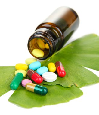 ginkgo biloba yaprakları ve ilaç şişesi üzerinde beyaz izole hapları ile