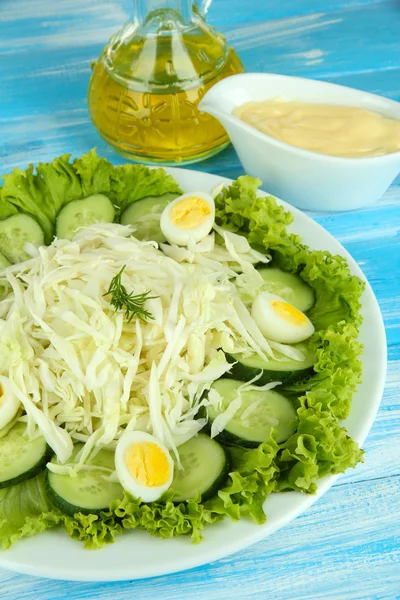 Вкусный салат с яйцами, капустой и огурцами на синем столе — стоковое фото