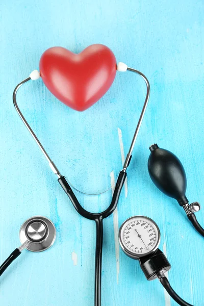 Tonometer, stethoscope and heart on wooden table close-up — Stock Photo, Image