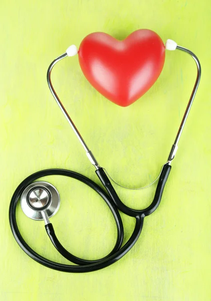 Stethoscope and heart on wooden table close-up — Stock Photo, Image