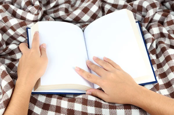 Book in hands on plaid background — Stock Photo, Image