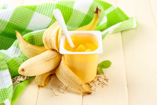 Iogurte saboroso com pedaços de frutas frescas, biscoitos e flocos, na cor de fundo de madeira — Fotografia de Stock