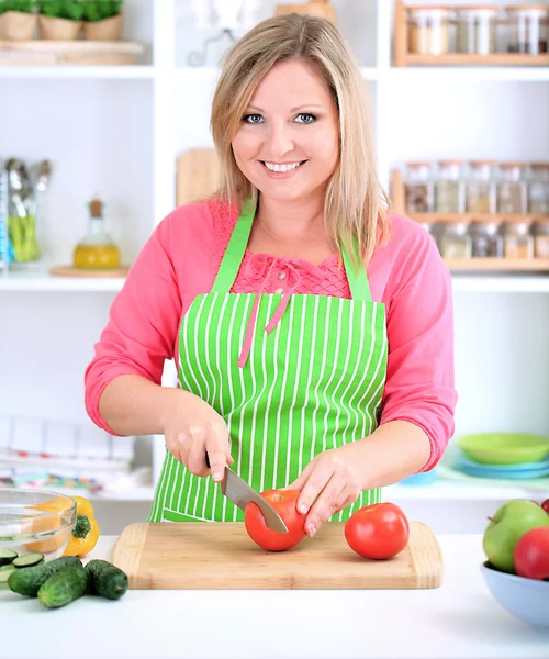 Glada leende kvinna i köket håller färska grönsaker i hennes händer — Stockfoto
