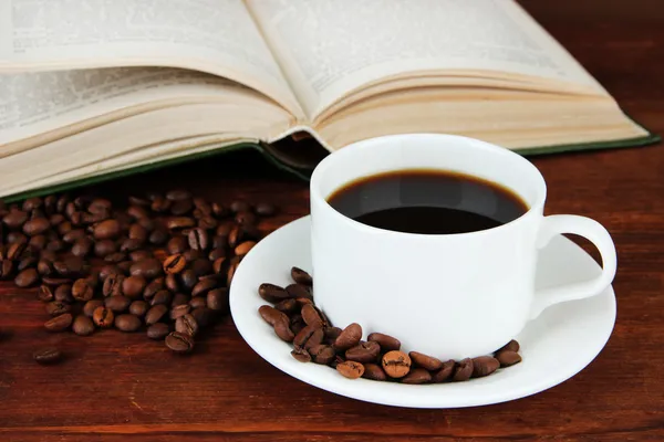 Tazza di caffè con chicchi di caffè e libro su sfondo di legno — Foto Stock