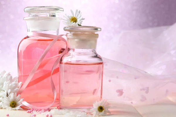 Bouteilles en verre avec essence de couleur, sur fond rose — Photo