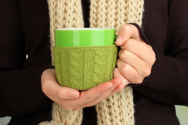 Cup with knitted thing on it in female hands close up — Stock Photo, Image