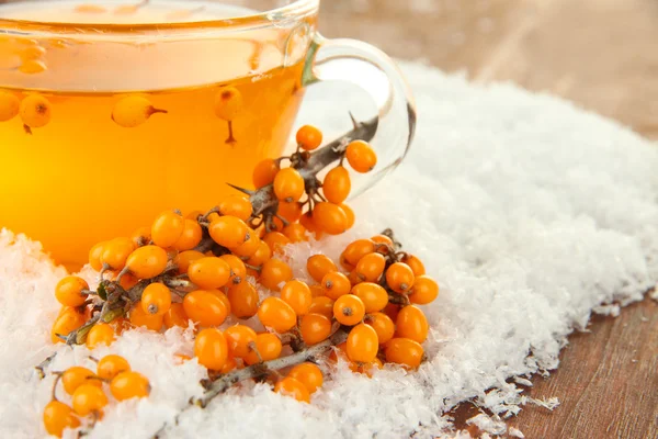 Branches of sea buckthorn with tea and snow on wooden background — Stock Photo, Image