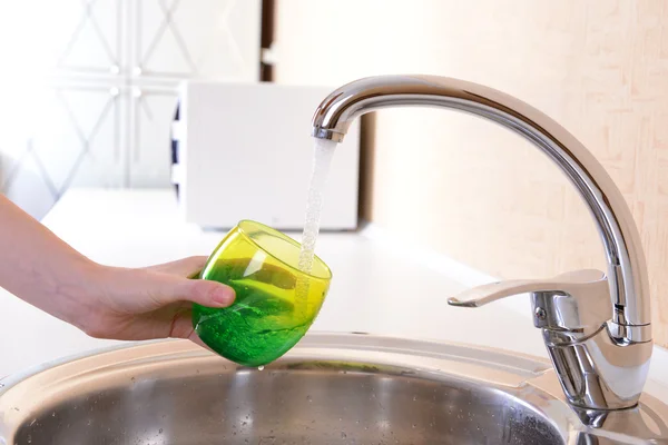 Hand hält Glas Wasser aus Küchenarmatur gegossen — Stockfoto