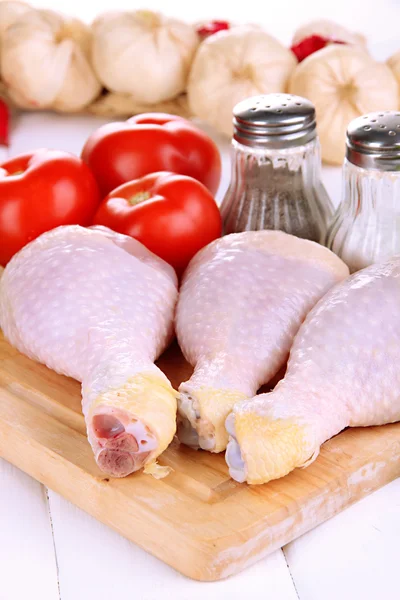 Pernas de frango cru na tábua de madeira de perto — Fotografia de Stock